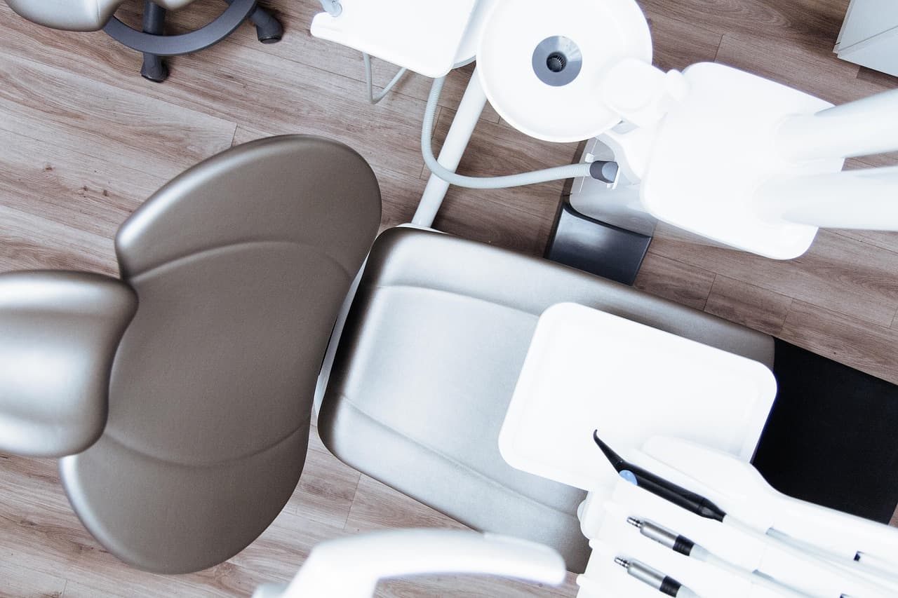 Empty dental chair with overhead light and handpieces in a modern surgery, viewed from above