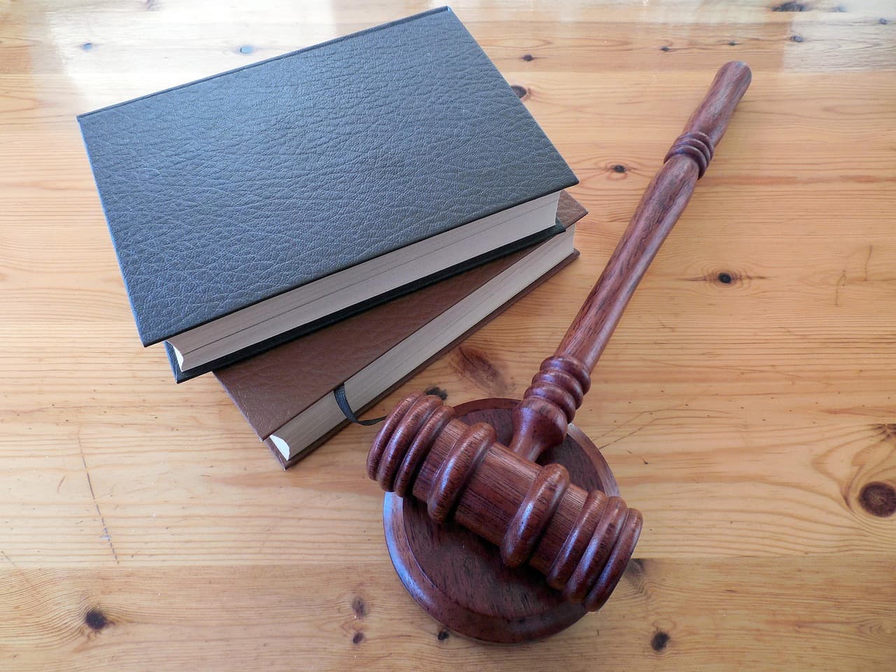 Wooden gavel and sound block beside two stacked law books on a pine desk